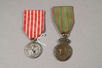 two medals on a white surface with a red, green and white ribbon