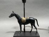 statue d'un cheval sellé, posée sur un socle surmonté d'une lampe