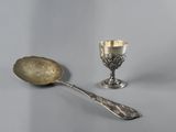 a silver spoon and a silver cup on a table