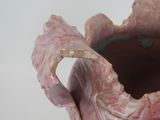 a pink vase with a large leaf inside of it