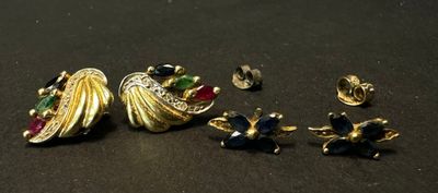 two pairs of earrings and a ring on a black surface