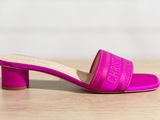 une sandale rose de la marque Muler, dotée d'un talon carré reposant sur une semelle en bois