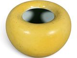 a yellow vase with a hole in it on a white surface