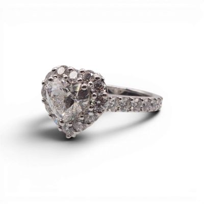 un gros plan d'une bague en diamant en forme de cœur sur fond blanc