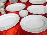 many plates and cups on a table with a red table cloth