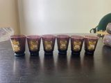 six glasses sitting on a table next to a book