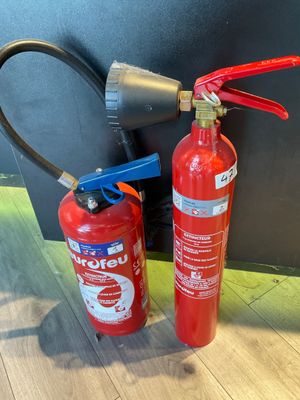 a fire extinguisor and a fire extinguisor next to each other