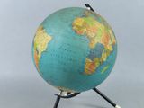 un globe bleu et vert posé sur un socle en bois