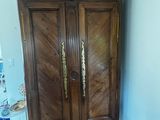 a wooden armoire in the corner of a room with tile flooring