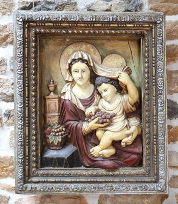 tableau représentant une femme tenant un enfant dans ses bras, encadré et accroché à un mur de briques