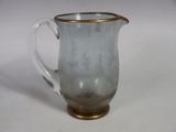 a glass pitcher with a gold rim sitting on a table