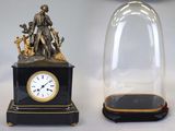 deux horloges posées sur une table, sous un dôme en verre