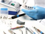une personne portant un gant bleu et tenant une brosse à dents ainsi que quelques outils