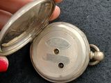 a person holding a silver pocket watch in their hand