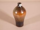 a brown and black vase sitting on a white surface