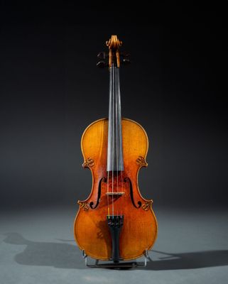 an old violin sitting on a stand against a black background