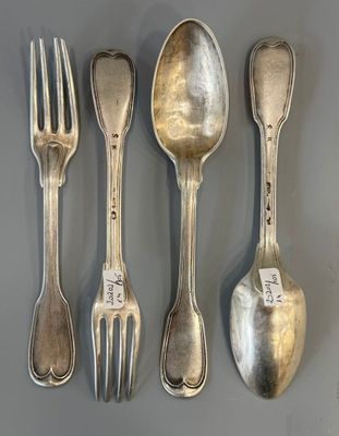 quatre cuillères en argent et une fourchette posées sur une table, accompagnées d'une étiquette de prix