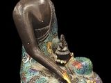 statue of a seated buddha with a bowl of flowers on a black background