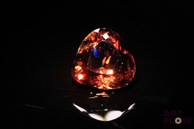 a close up of an orange diamond on a black surface