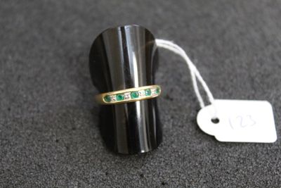 une image représentant une bague sertie d'émeraudes sur un fond noir