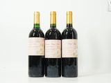 trois bouteilles de vin sont alignées sur une surface blanche