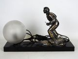 a silver statue of a man on a skateboard next to a white ball