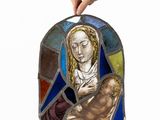 a hand holding a stained glass piece with a picture of jesus