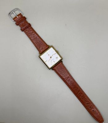 une montre marron avec un cadran blanc posée sur une table