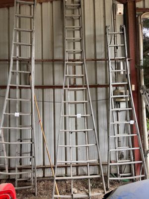 plusieurs échelles appuyées contre un mur dans un garage