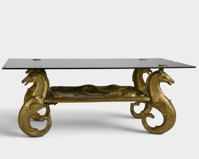 a gold coffee table with a glass top and two seahorses on it