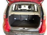 the back of a red car with its trunk open and a bed in the trunk