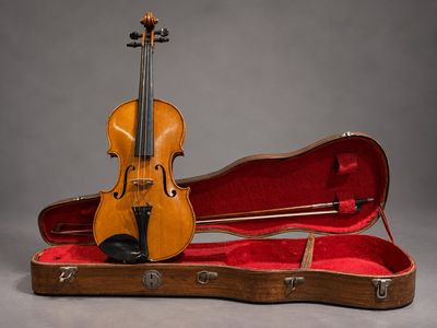an old violin sits in a case on a gray background
