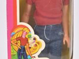 une poupée dans une boîte rose, vêtue d'un t-shirt rouge et d'un jean bleu