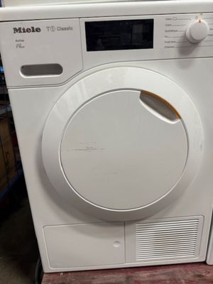 une machine à laver blanche posée à même le sol
