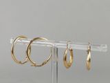 trois paires de boucles d'oreilles créoles en or présentées sur un présentoir transparent