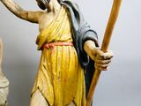 une statue représentant un homme tenant un bâton et un bâton