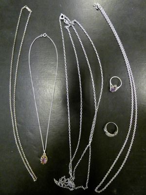 de nombreux colliers et bagues en argent posés sur un fond noir