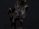 bronze statue of a boy sitting on a chair holding a book