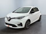 La voiture blanche est garée dans une pièce au sol noir.