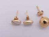 three pairs of gold plated earrings and a ball on a white surface