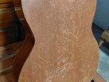 an old guitar sitting on top of a wooden stand in a room