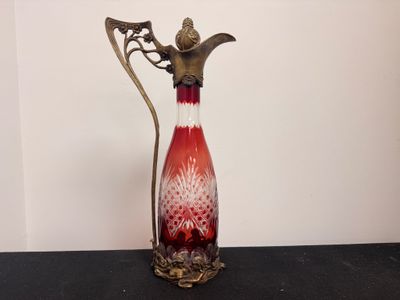 un vase rouge et blanc muni d'une poignée en métal, posé sur une table