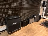 a room that has a bunch of speakers and a guitar on the floor