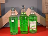 three bottles of green liquid sitting on a red table