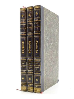 trois livres sont empilés sur une surface blanche