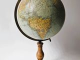 un vieux globe terrestre posé sur un socle en bois, sur fond blanc