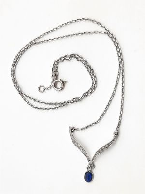 un gros plan d'un collier composé d'une pierre bleue montée sur une chaîne