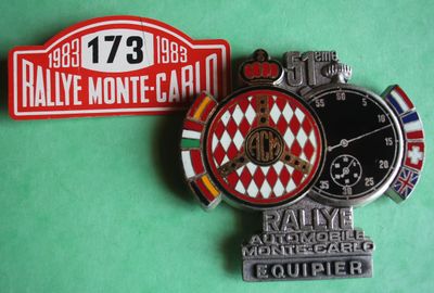 two badges are shown on a green surface with a red and white sign