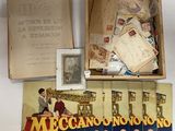 une boîte ouverte sur laquelle figure l'image d'un homme assis sur une table, à côté d'une pile de vieilles cartes postales