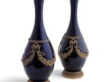 pair of blue vases with gold decoration on stands against a white background